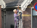 The Dutch dedication to cleanliness. This woman is risking her life to wipe the gutters of her house.